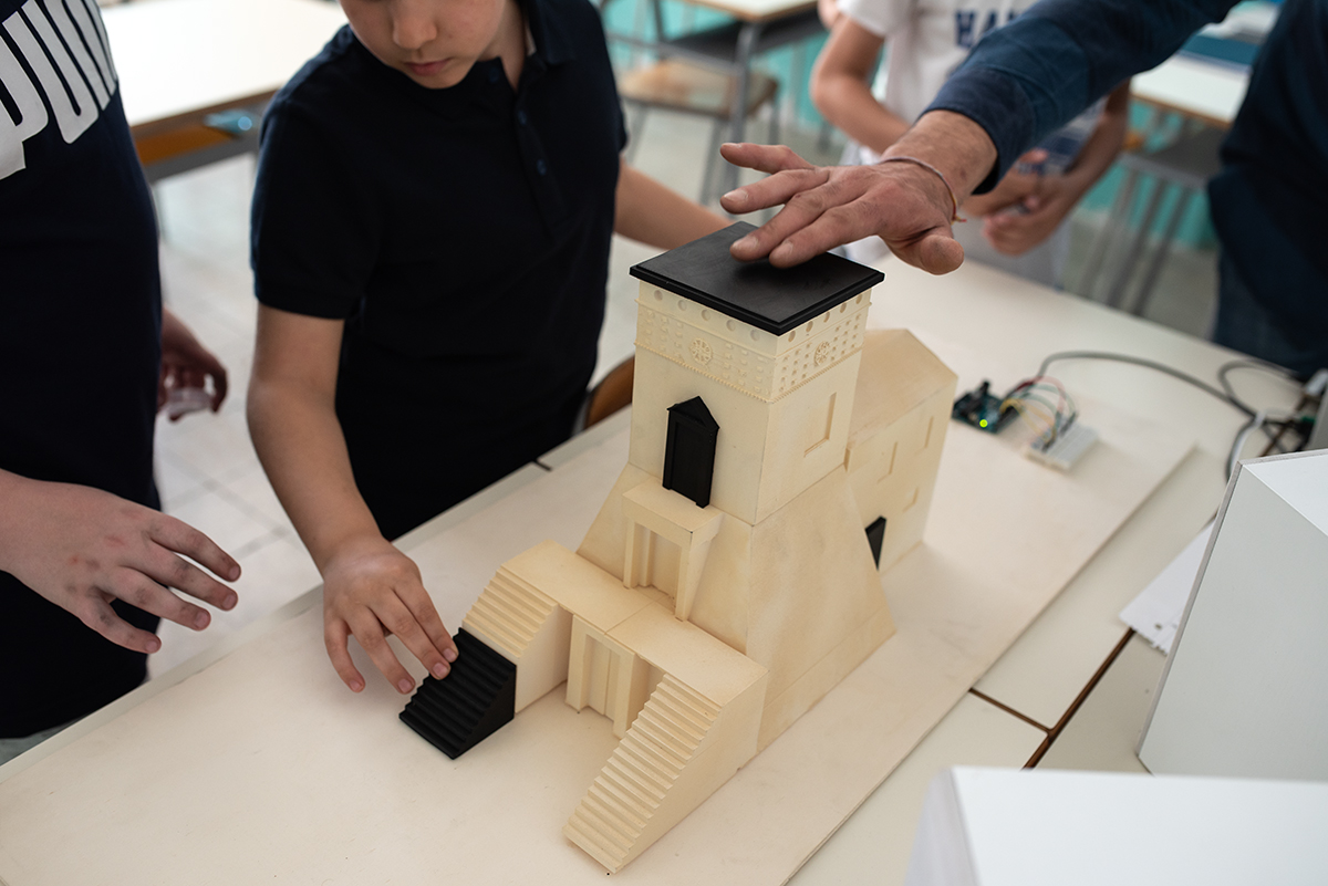 Una mano tocca la parte nera conduttiva della Torre di Bene durante un laboratorio Hi-Storia